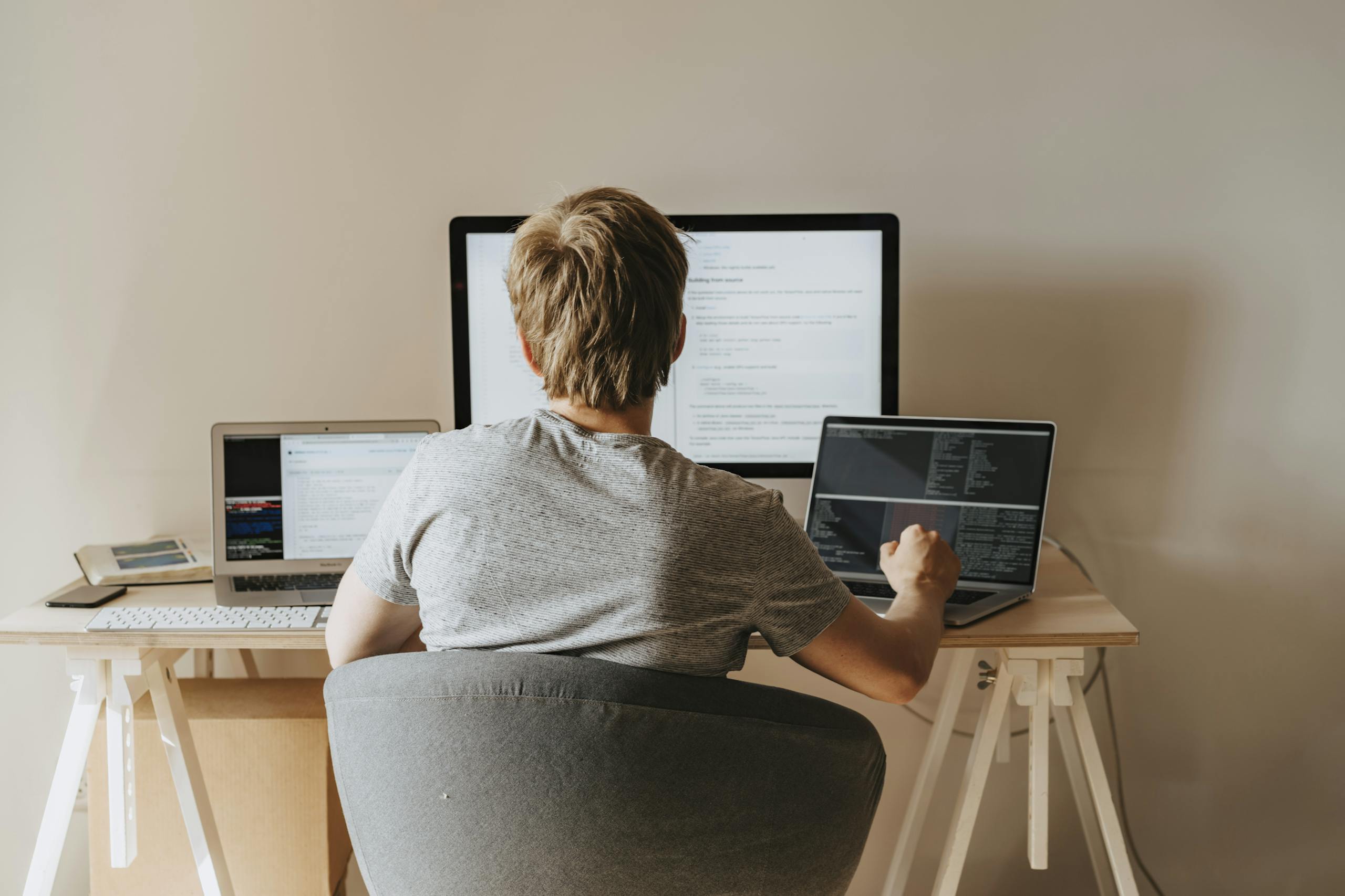 Teen programming with multiple laptops in a modern workspace. Ideal for tech and education themes.